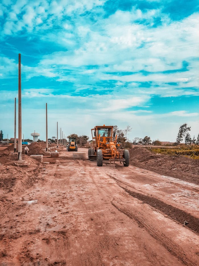 gallery-05 Yellow bulldozer working on a dirt road under a blue sky, ideal for construction themes.