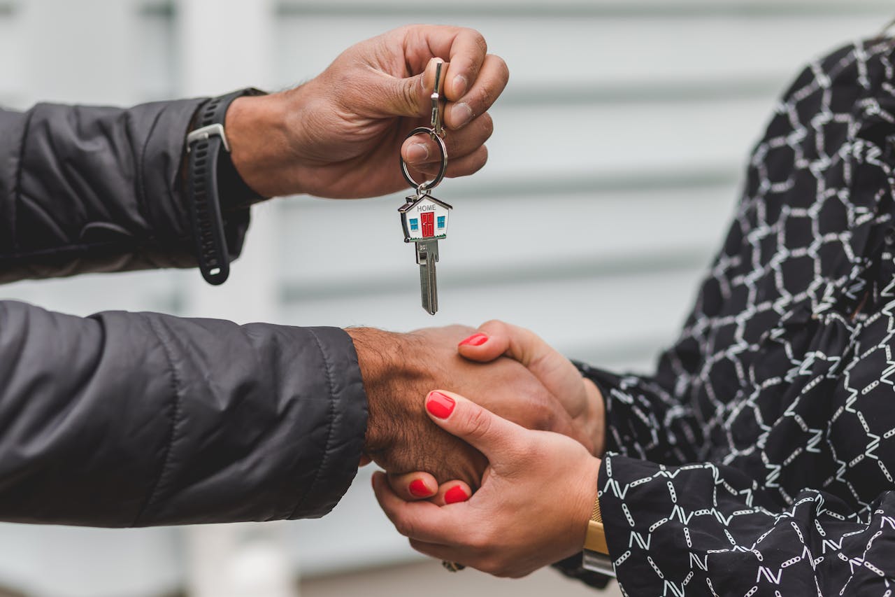 gallery-01 Close-up of a realtor handing over a house key to a new homeowner, symbolizing ownership and investment.